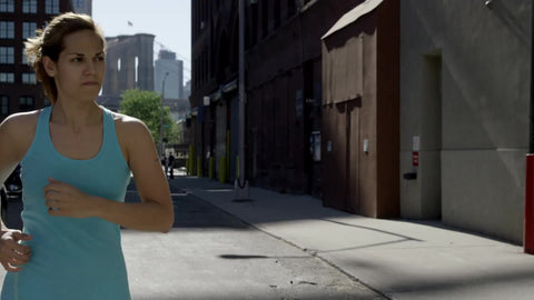 athletic woman jogging down street in slow motion - exercising outside on sunny day with Brooklyn Bridge in background in 1080 HD and 4K NYC