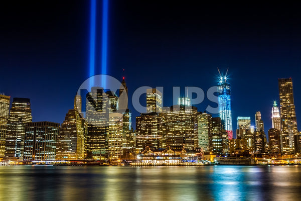 September 11th memorial beams on 911 over Manhattan skyline with Freedom Tower in red white and blue color lights