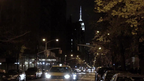 taxi cab on lower 5th Ave with Empire State Building in background at night