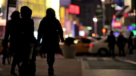 silhouettes walking in Times Square at night in winter - three women with luggage - tourists in Manhattan