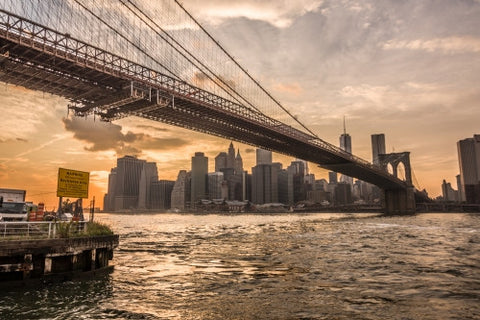 Brooklyn Bridge and East River with Manhattan skyline in background at sunset with beautiful orange sky in NYC