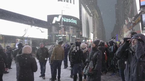 tourists looking at Revlon LCD screen in Times Square in winter - snowing at night
