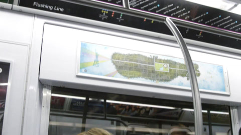 woman bobbing head to music with earbuds in riding subway train tilting down from map of Manhattan