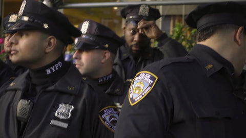 tracking shot of large group of NYPD police officers - faces and uniforms - lined up in street in NYC