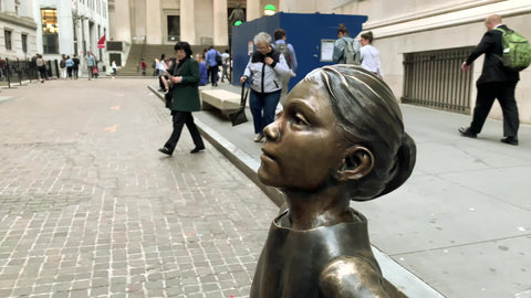 Fearless Girl Statue looking up at NYSE American flags and Kontoor KTB Listed ad New York Stock Exchange NYC