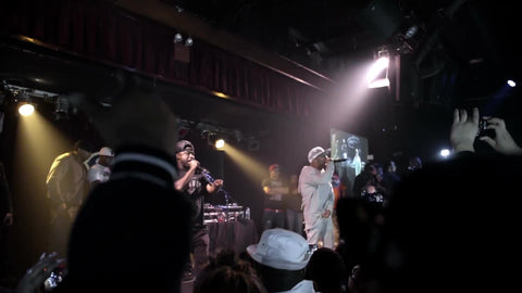 far shot of Mobb Deep rapping at live show - zooming into stage from crowd in slow motion