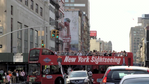 New York Sightseeing red tour bus turning corner on busy street