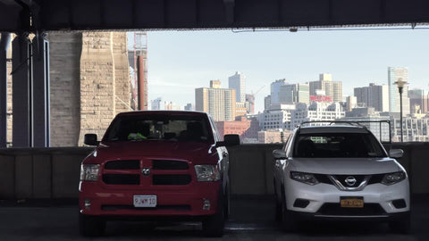 driving past parked cars under FDR Drive with Brooklyn Bridge and skyline buildings across East River Lower East Side LES Manhattan New York City NYC