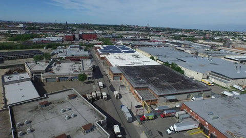 aerial of warehouses in the Bronx panning to Manhattan skyline in distance over river water in NYC