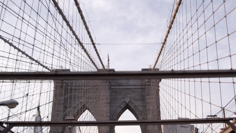driver's first person pov driving across Brooklyn Bridge with American flag on tower in NYC