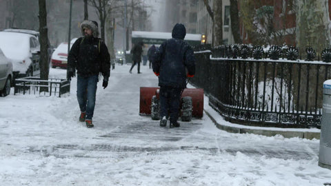 man plowing snow with snow plow in winter blizzard snowstorm - snowing in slow motion in Manhattan