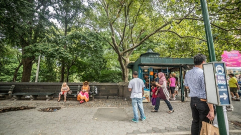 Columbus Circle with people in Midtown Manhattan on sunny summer day across the street from Central Park, trees with green leaves in NYC