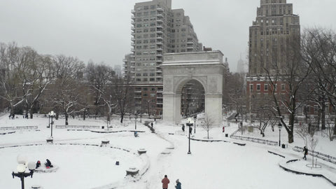 slow rising aerial over Washington Square Park arch white winter snow - blizzard snowing in NYC