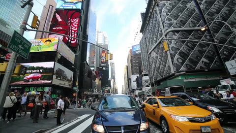 cars and taxi cab driving in traffic through Times Square during the day