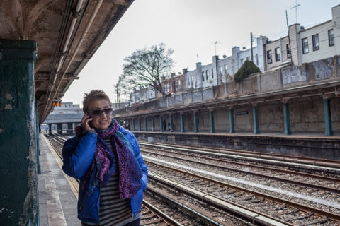 woman on cell phone - outdoor subway platform in winter - elevated train station tracks