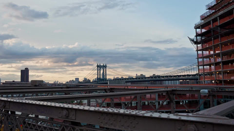 panning Manhattan skyline from Brooklyn Bridge at sunset with skyscrapers in background in NYC