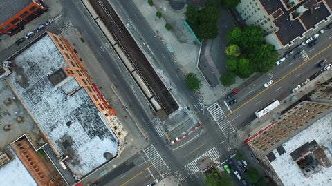 aerial of 1 Train entering tunnel - overhead view of subway and project building - moving over Harlem in NYC