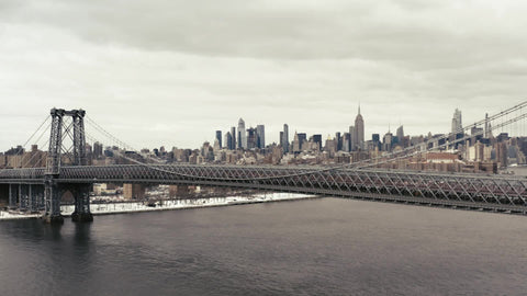 aerial moving forward toward Williamsburg Bridge and Empire State Building lateral tracking aerial drone shot with Manhattan skyline over East River New York City NYC