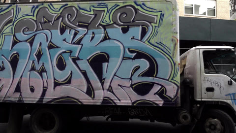 beautiful graffiti truck spray-painted with colorful art driving away in morning in NYC