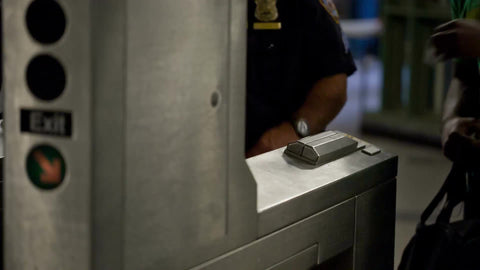 hand swiping metro card at subway station turnstile - close-up