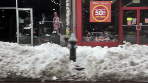 driving past Lower East Side street with graffiti, snow, people in cold winter New York City NYC