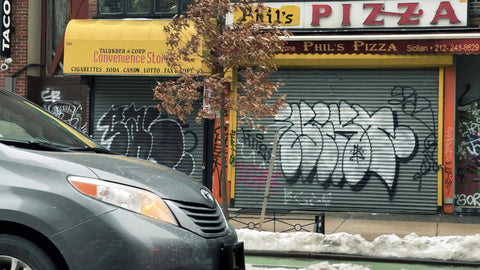 graffiti piece on gated pizza shop storefront - pizzeria closed during covid pandemic lockdown-