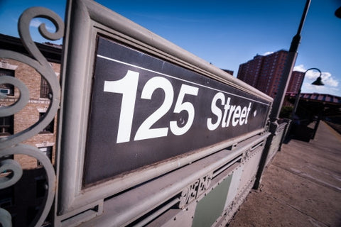 125th street sign at elevated subway station platform and project housing in Uptown Manhattan NYC