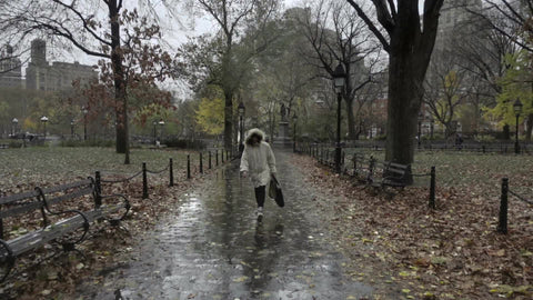 woman in coat walking in Washington Square Park in slow motion on wet rainy day in fall